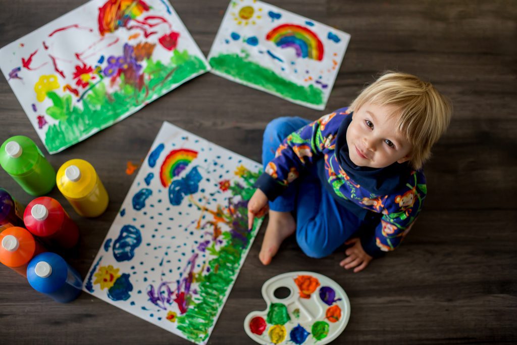 Preschool boy painting with colors, making finger prints on the paper